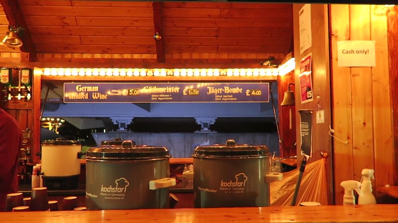 German beer and hot drinks stall glowing beneath Christmas garlands at Southbank market
