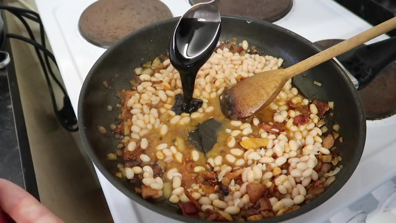Black treacle being added to homemade smoky baked beans