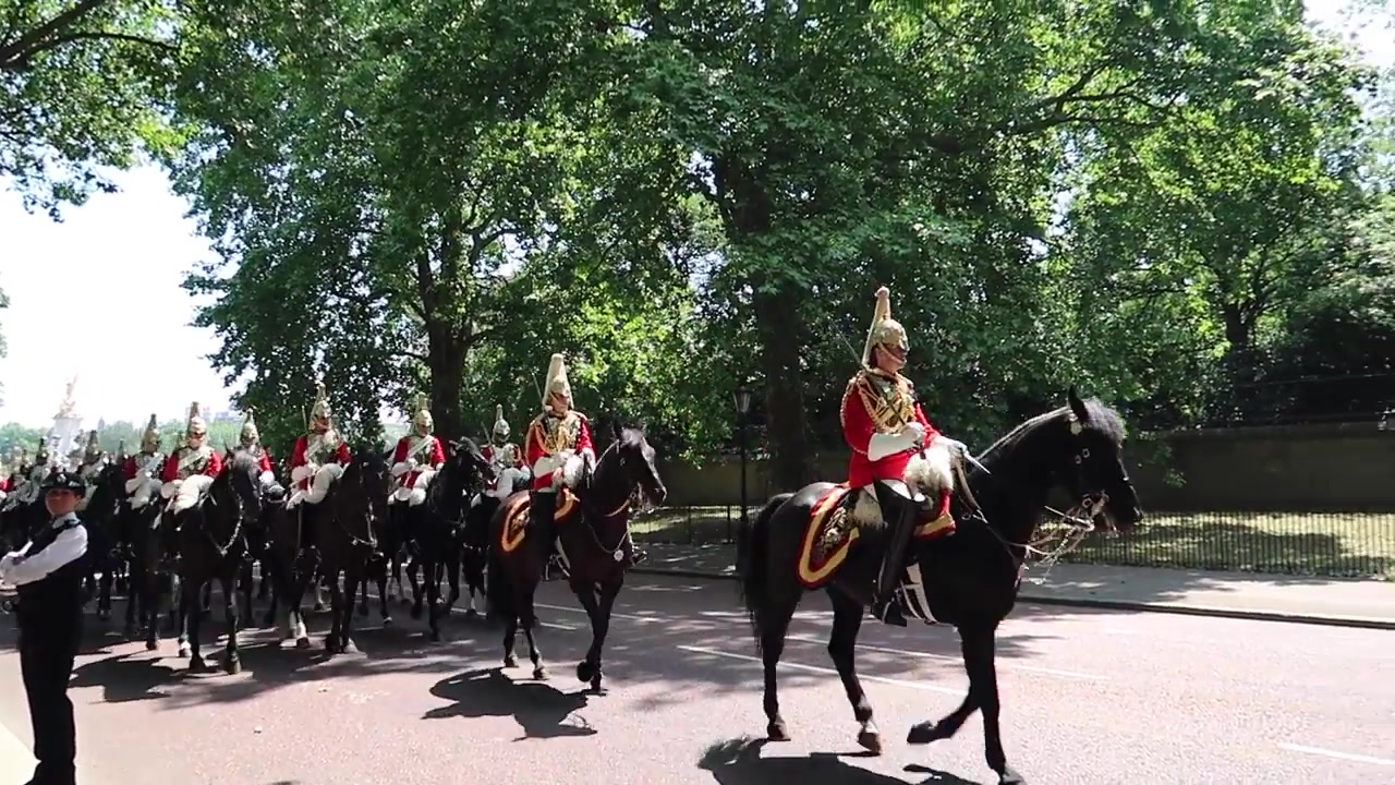 Mounted guards in red and black ceremonial uniforms riding beside St James’s Park in 2018