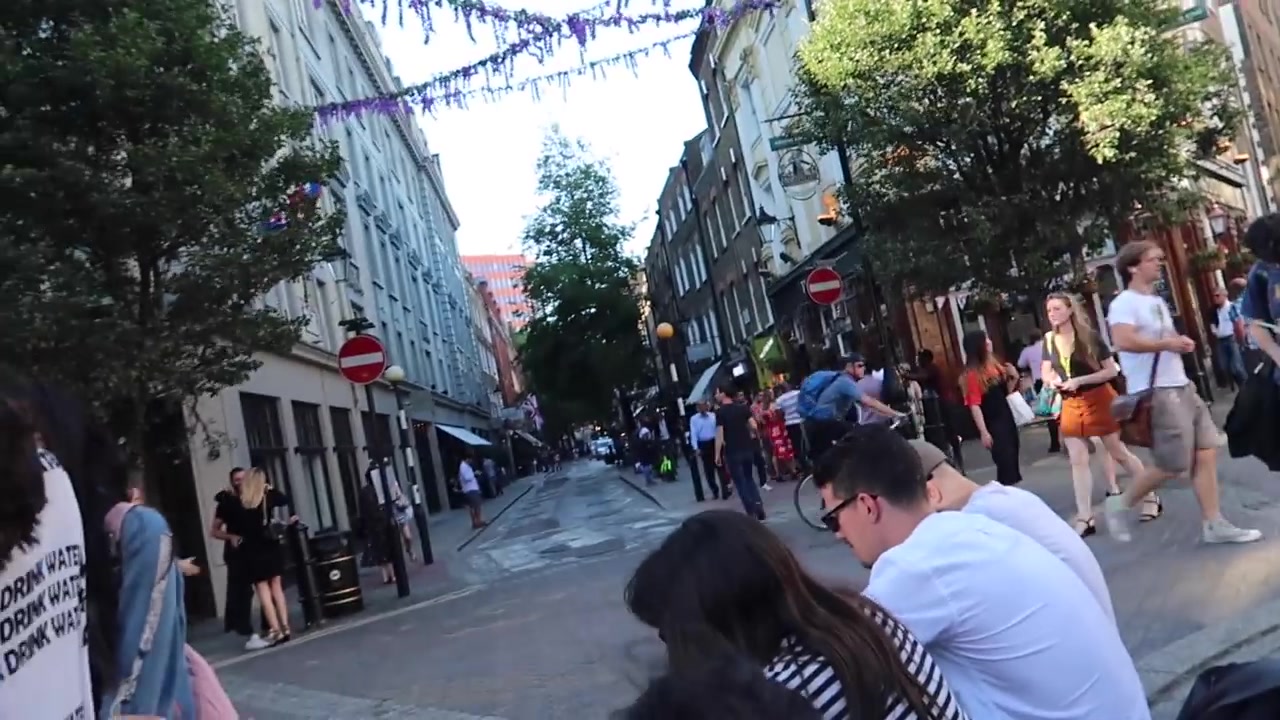 People sitting and walking through Neal's Yard in Covent Garden on a summer evening