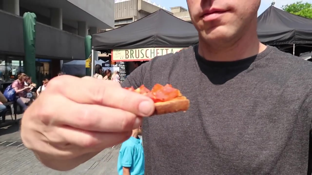Tomato bruschetta held in front of a market stall at Southbank Centre Food Market