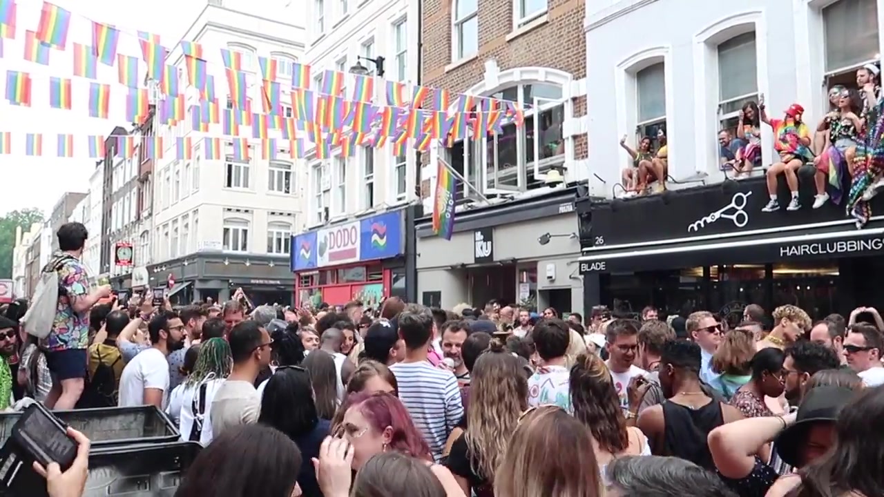 Rainbow bunting above a crowded London street.