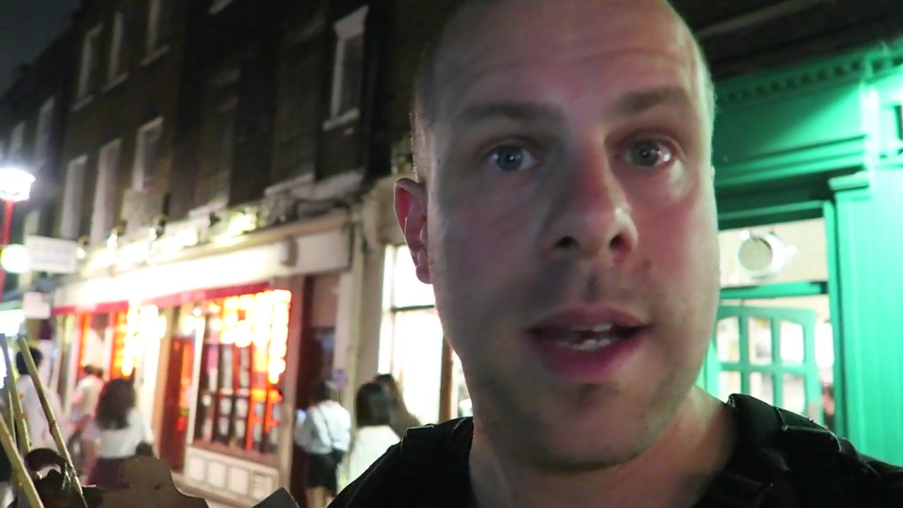 Barry outside the lit restaurant and takeaway fronts in Chinatown at night