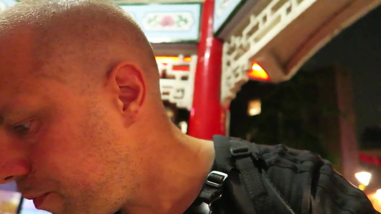 Barry tasting takeaway skewers beneath the decorated Chinatown pavilion