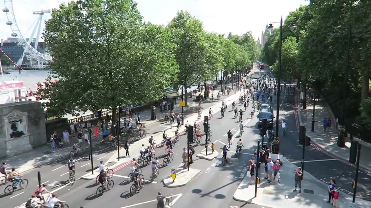 Cyclists along Victoria Embankment with the London Eye across the Thames
