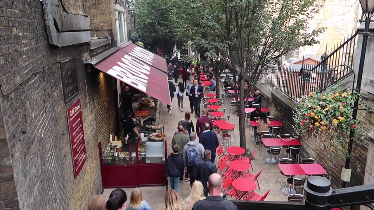A view down the market-side path with red café tables.