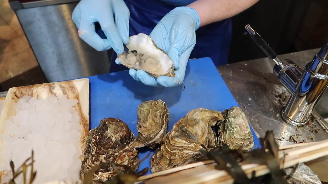Trader opening an oyster at a Borough Market seafood stall