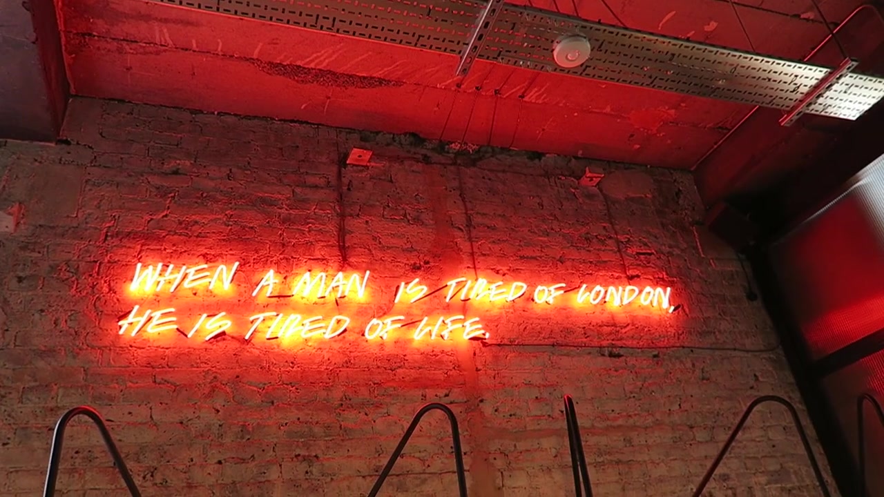 Red neon lettering on an exposed brick wall inside London Grind
