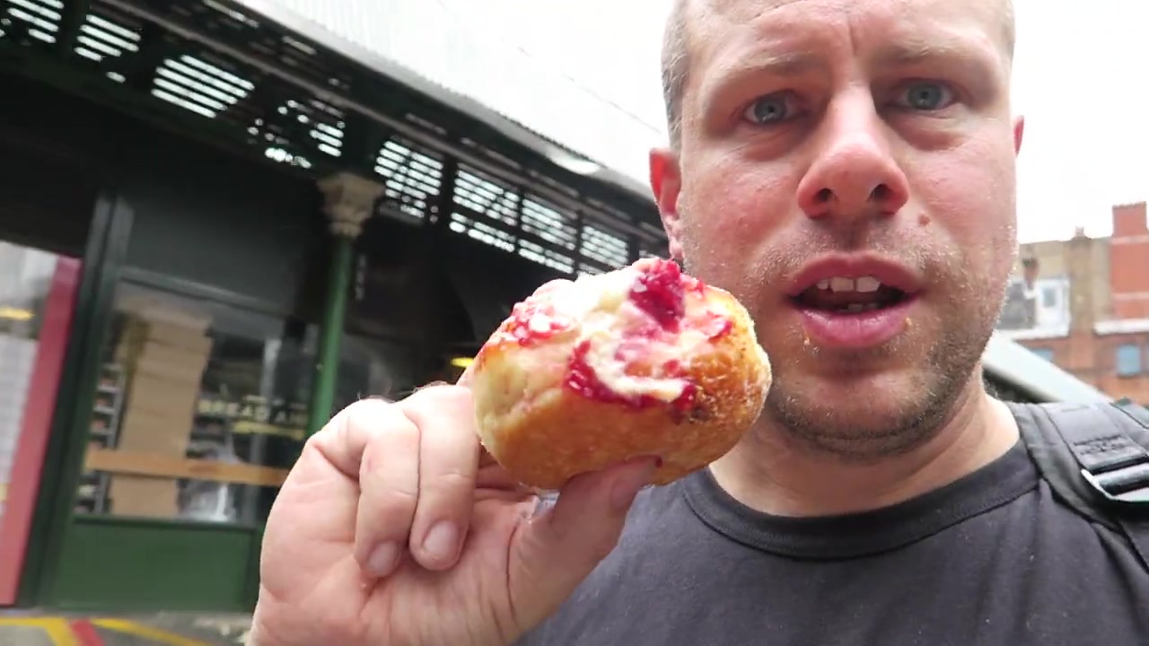 Barry Roberts holding a raspberry-topped Bread Ahead doughnut
