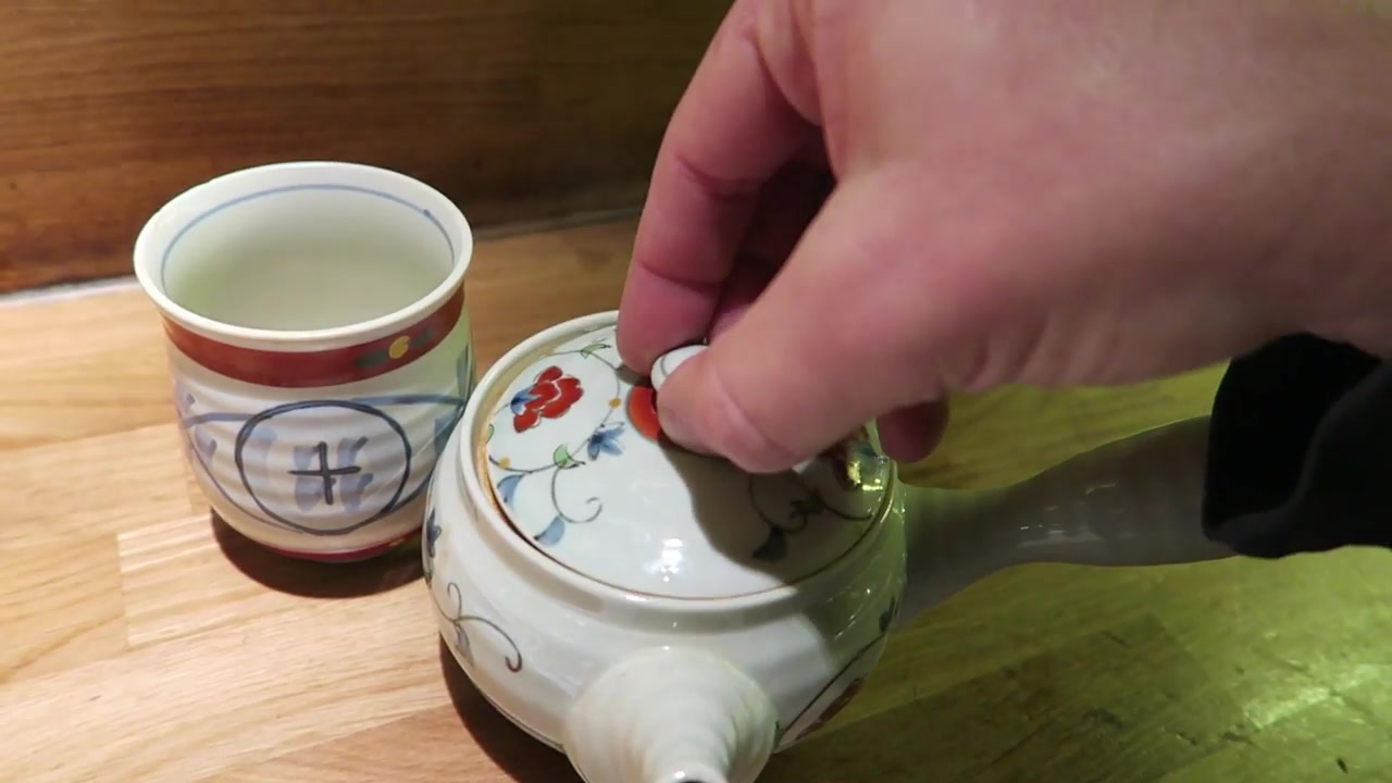 Green tea in a decorated cup beside a teapot at Shoryu
