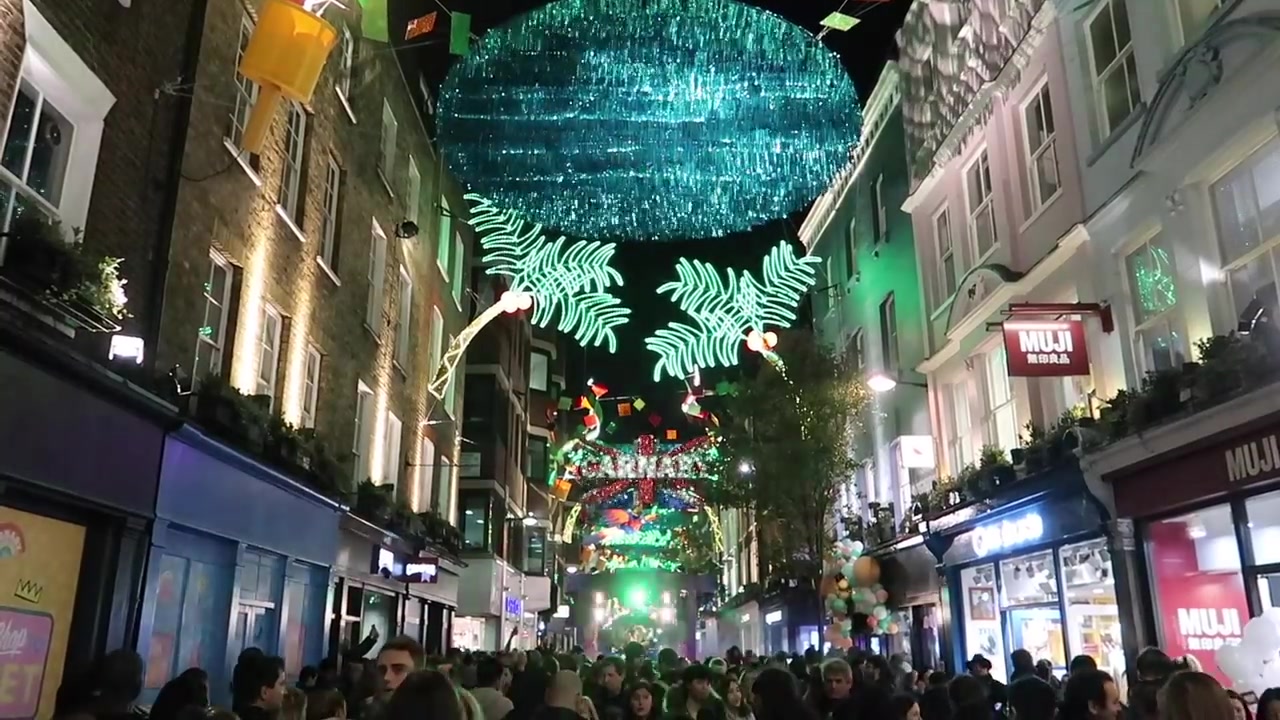 Crowds beneath the blue canopy and green palm lights on Carnaby Street.