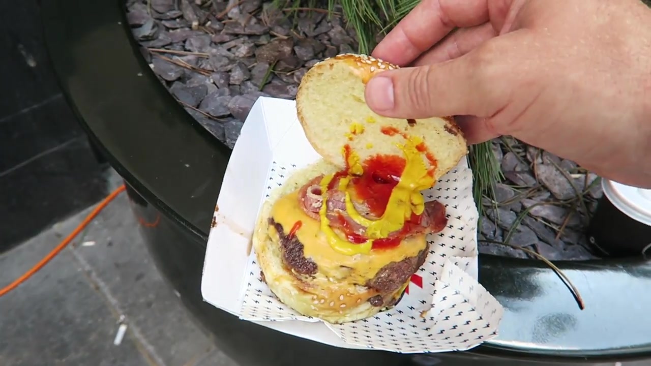 A bacon cheeseburger in a paper tray outside The Diner