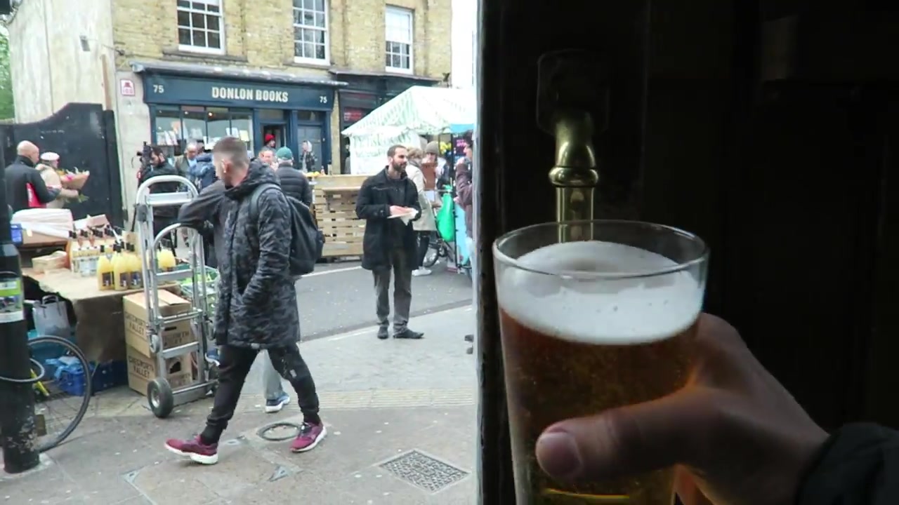 A pint of beer at the Cat and Mutton with Broadway Market stalls and Donlon Books beyond