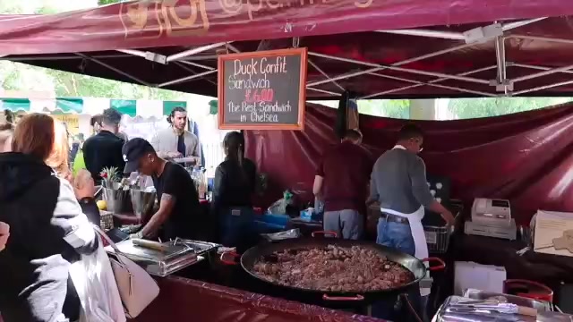 Duck cooking in a wide pan under a red market awning at Partridges