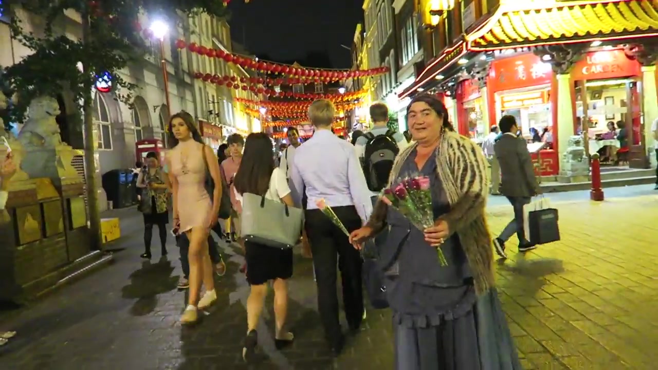 People walking beneath lanterns and illuminated Chinatown signs at night