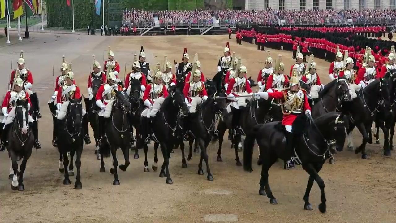 Mounted cavalry in ceremonial uniforms passing the spectators