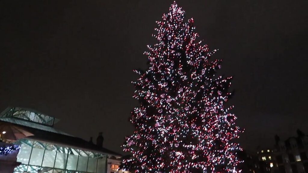 Covent Garden’s tall Christmas tree glowing with pink and white lights in 2017.