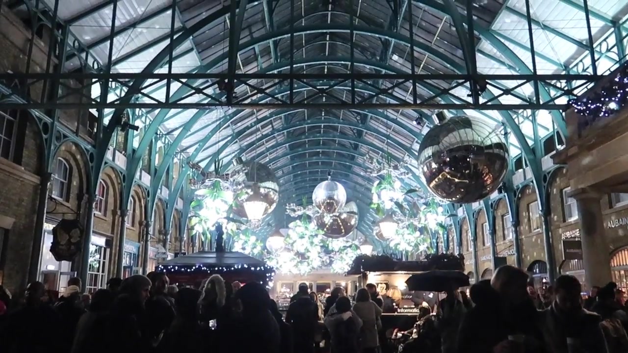 A crowded market hall beneath the glowing mistletoe decorations.