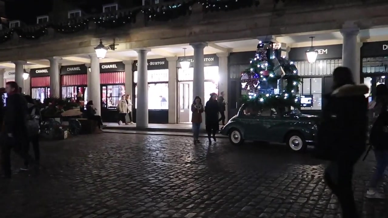 Small decorated car carrying a Christmas tree outside the market shops