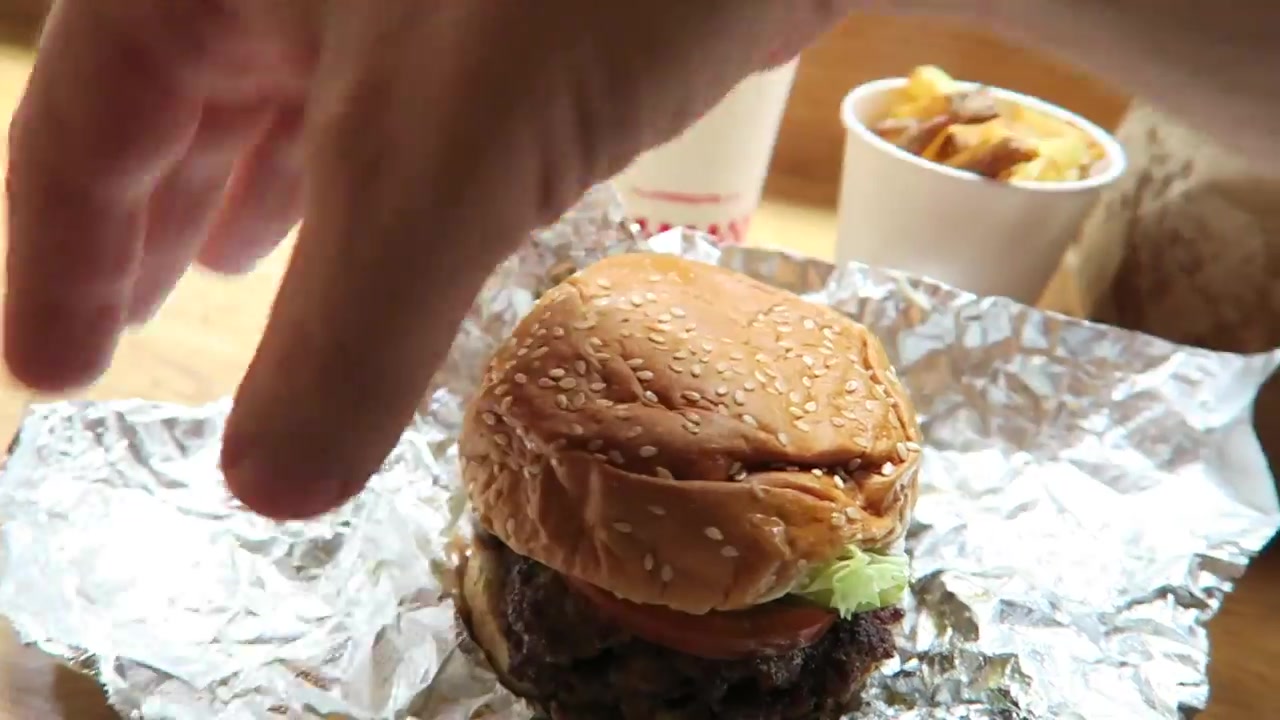A burger and cup of fries on a table at Five Guys