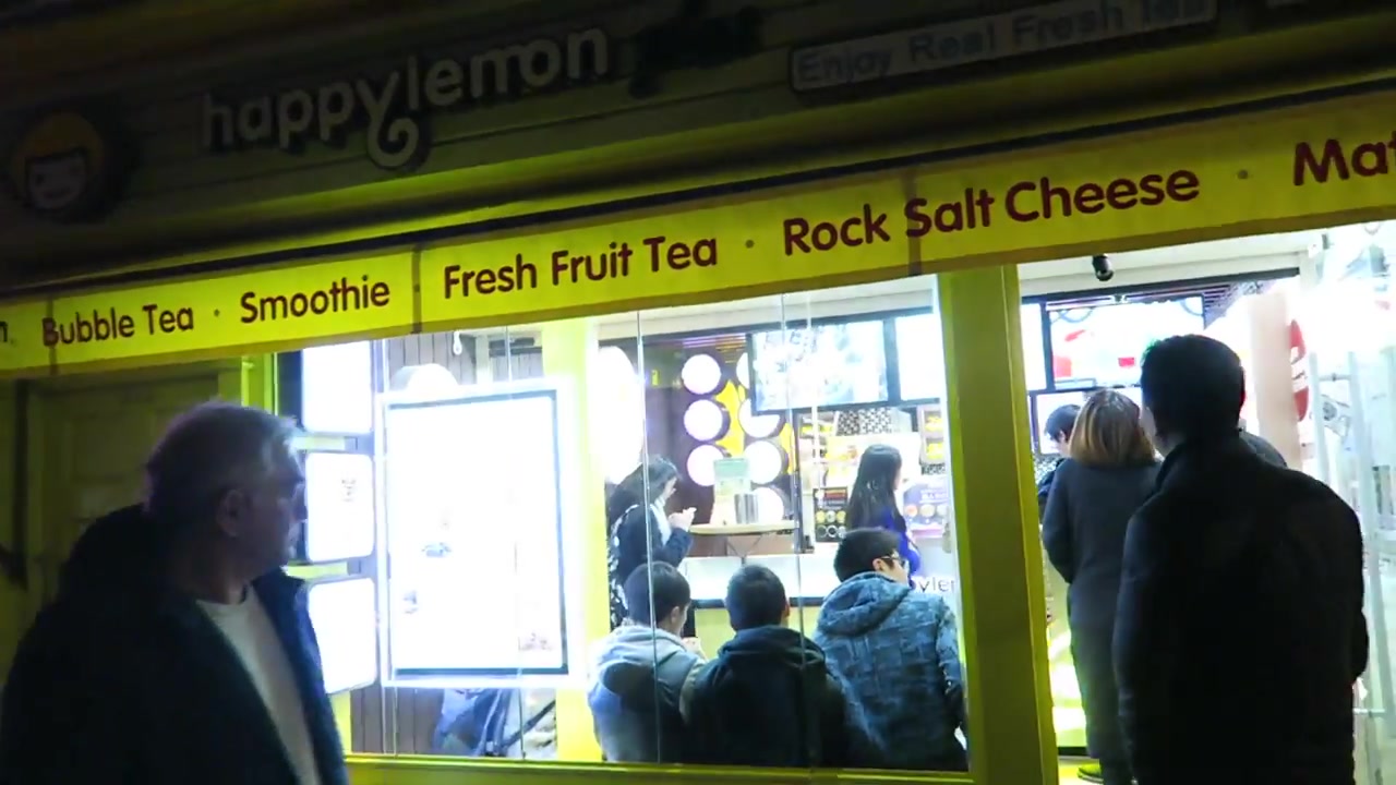 Happy Lemon shopfront with customers beneath its yellow drinks sign