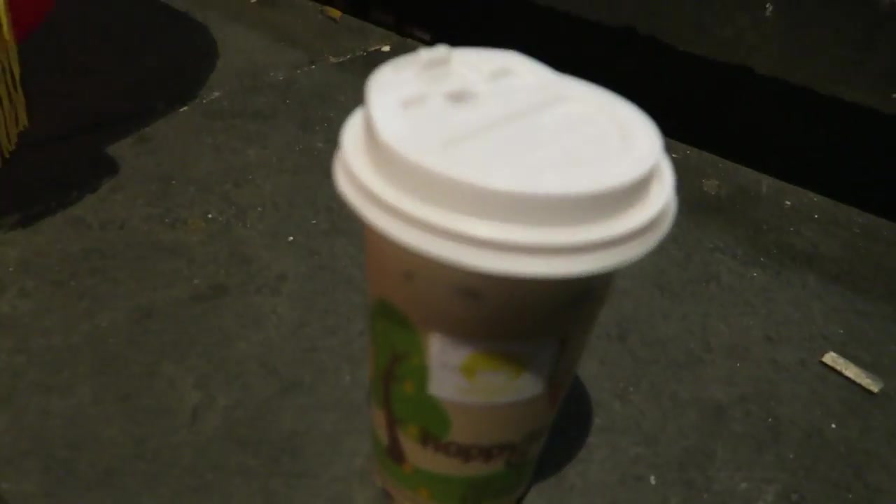 Happy Lemon takeaway cup with a white lid on a stone surface
