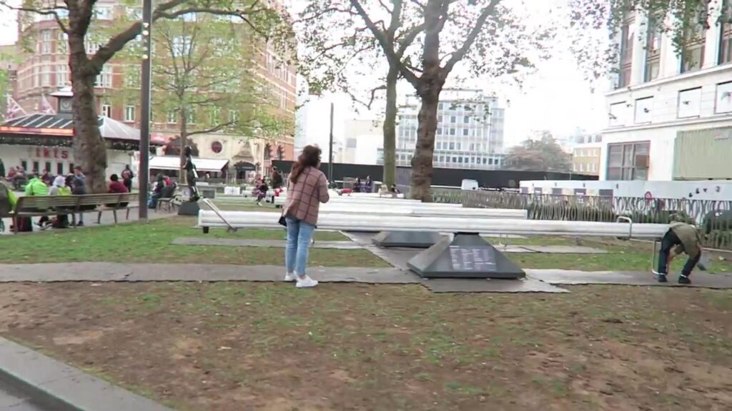 Visitors beside the Impulse Leicester Square seesaws arranged in rows in the gardens