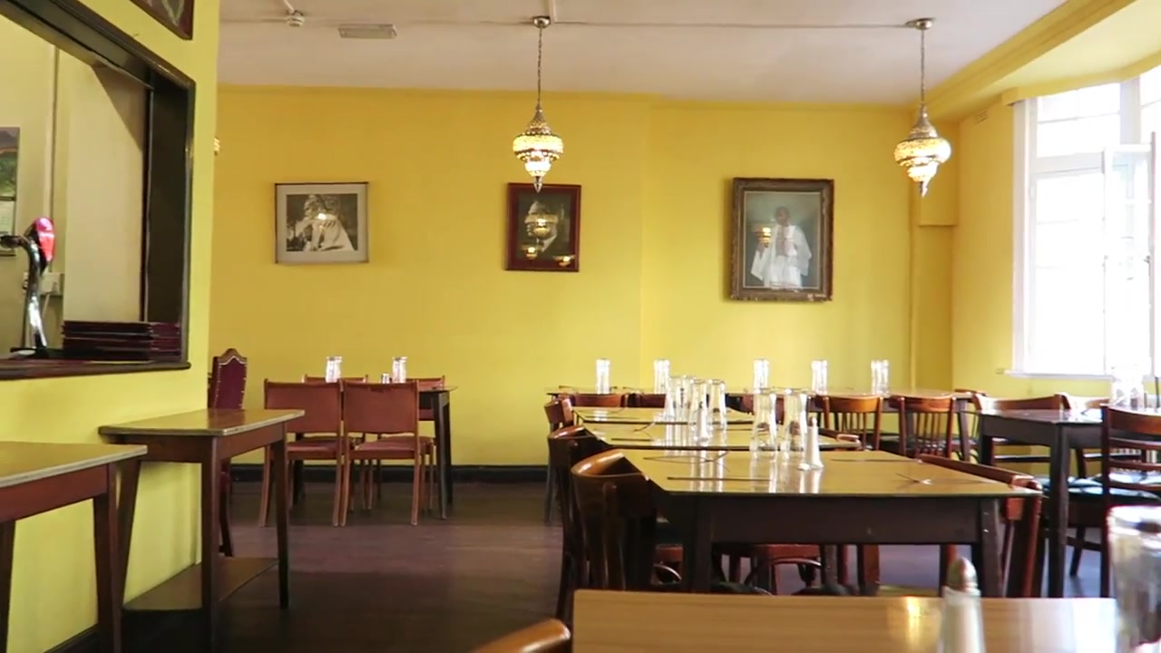 Yellow dining room with wooden tables and portraits at the India Club