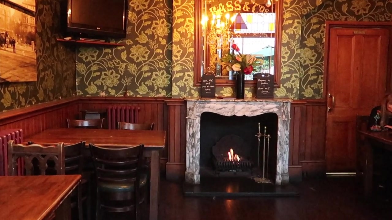 A fire, patterned wallpaper and wood panelling inside the Warwick Castle pub.