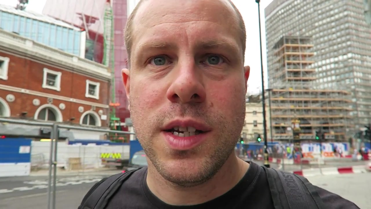 Barry filming in a black T-shirt on a grey London day with construction behind him