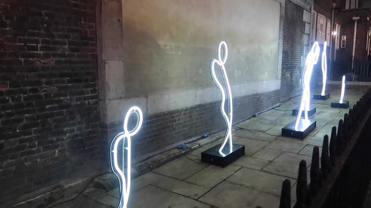 Glowing figures in an outdoor Lumiere installation.