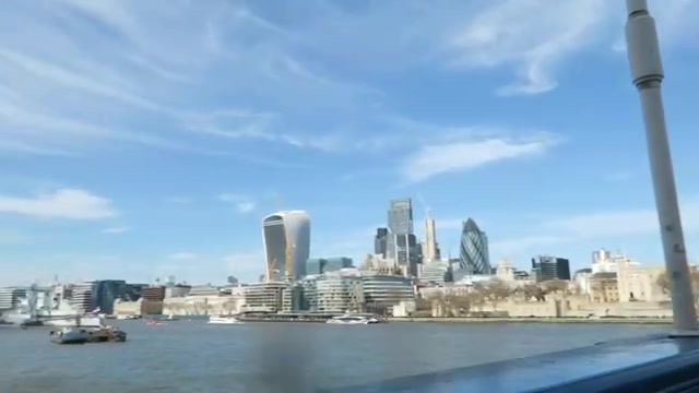 City of London towers across the Thames under a blue sky