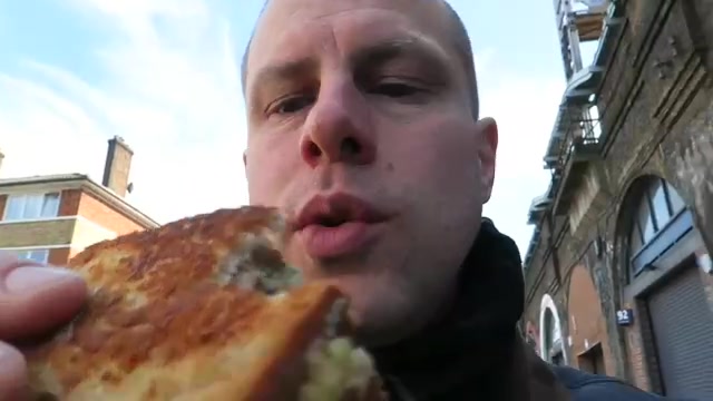 Barry holding a golden toasted cheese sandwich beside the railway arches