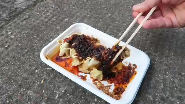 Dumplings covered with sauce and chilli in a takeaway tray