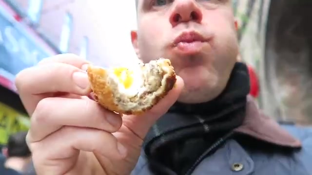 Barry holding a cut Scotch egg showing the egg and dark filling