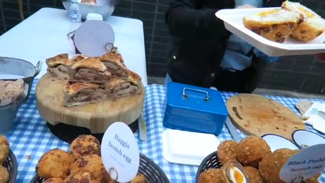 Scotch eggs and pies displayed on a blue checked market table