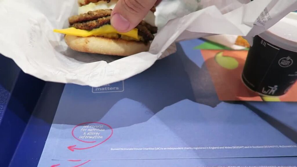 Double sausage and egg McMuffin with cheese beside a coffee cup