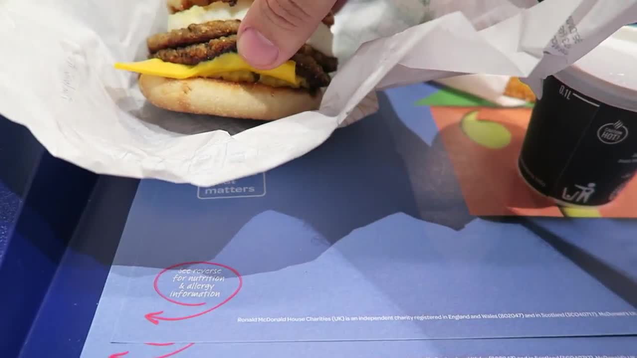 Double sausage and egg McMuffin with cheese beside a coffee cup