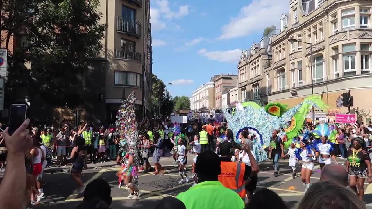 Performers in colourful feathered costumes crossing the Carnival parade route