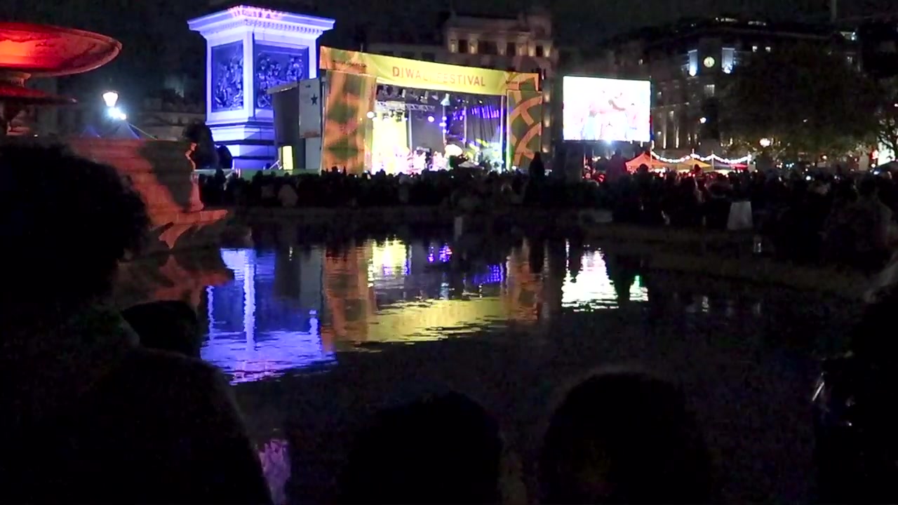 Diwali stage lights reflected in a Trafalgar Square fountain.