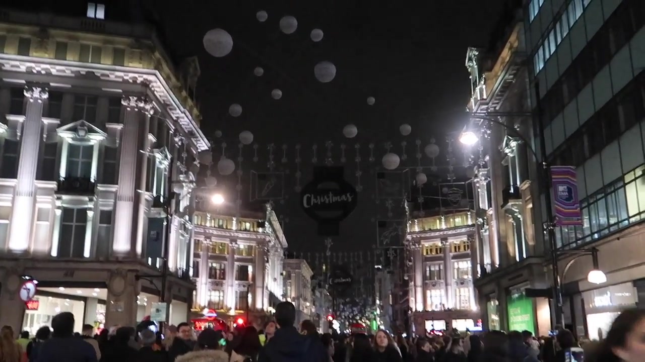 Crowds wait beneath the unlit Christmas decorations on Oxford Street.
