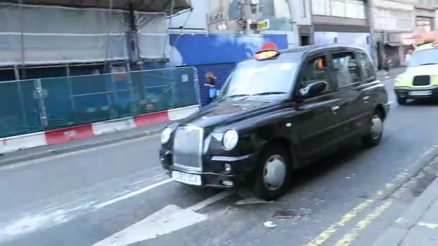 Black taxi passing building works on Oxford Street in 2016