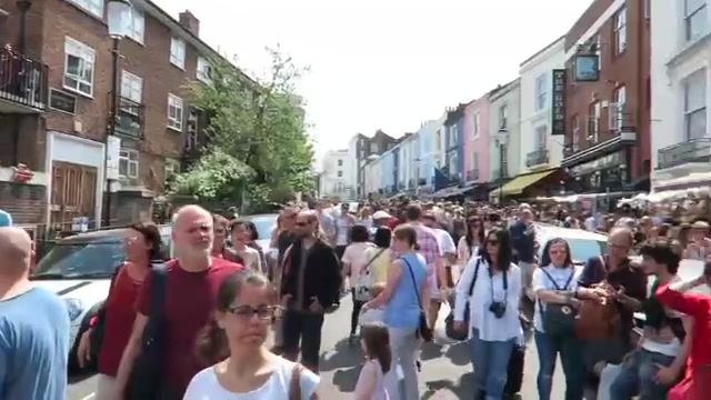 Saturday shoppers filling Portobello Road Market beneath colourful shopfronts