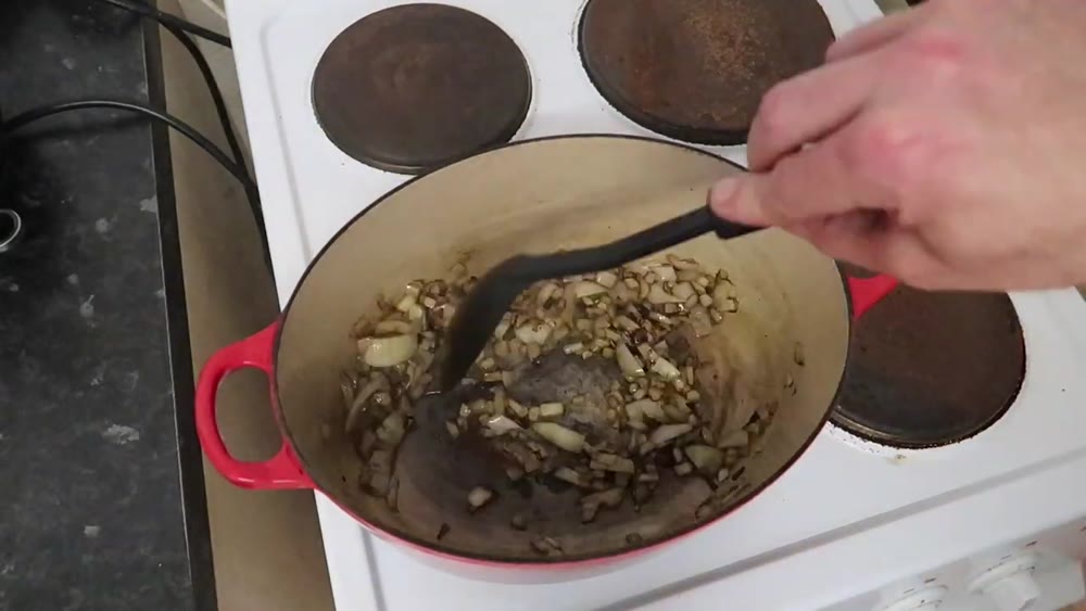 Preparing the aromatic base for lamb shanks in a red casserole