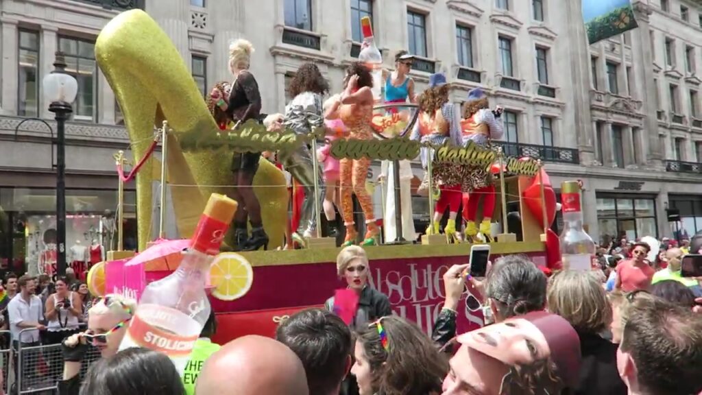 Performers beside a giant golden high-heeled shoe on a Pride parade float