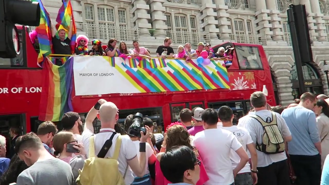 Red Mayor of London bus decorated with rainbow stripes at Pride