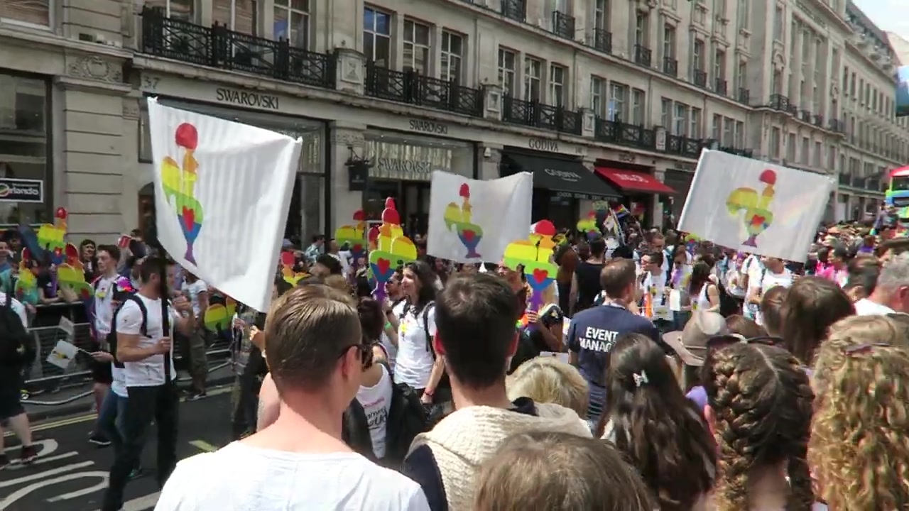 White banners with rainbow-coloured figures among Pride marchers