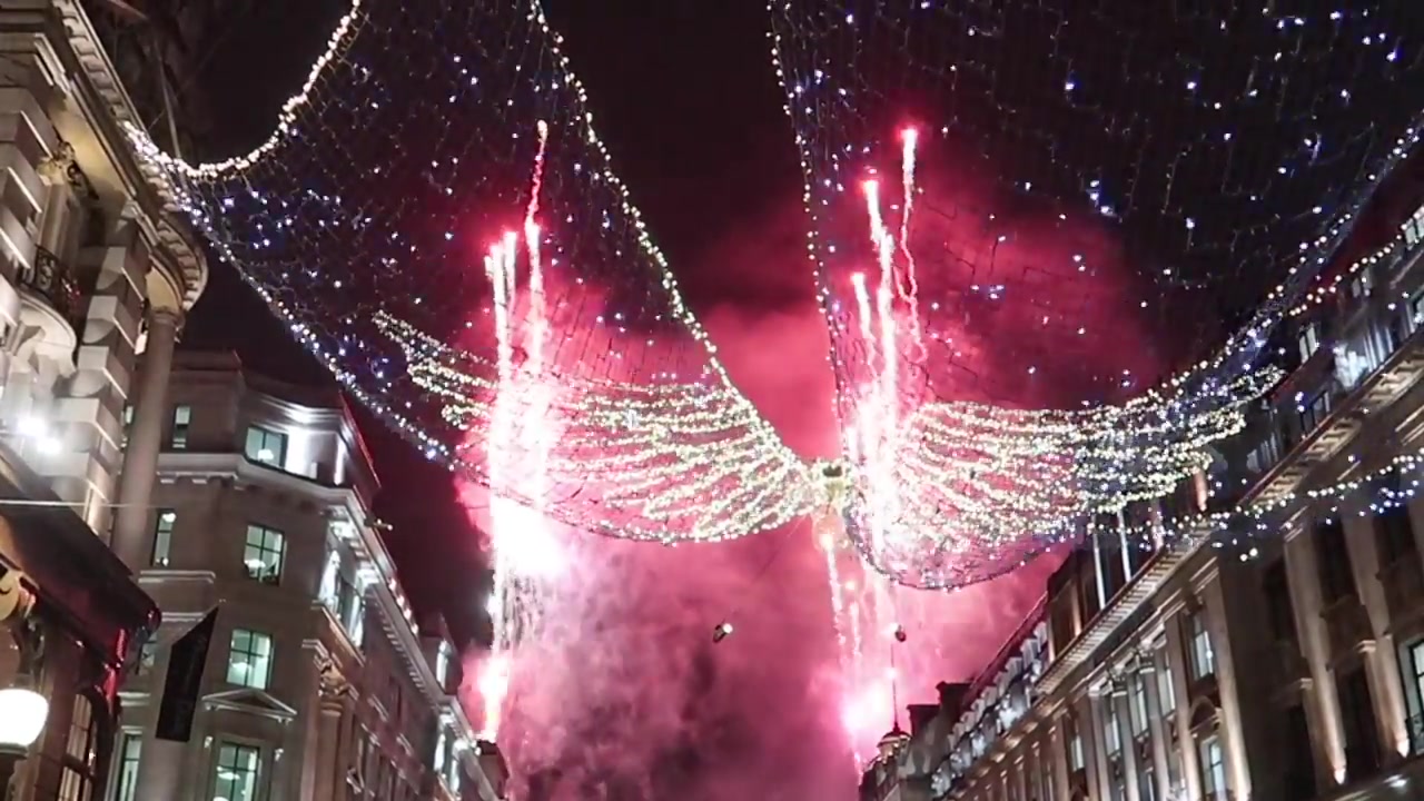 Red fireworks and drifting smoke above Regent Street’s Christmas angels.