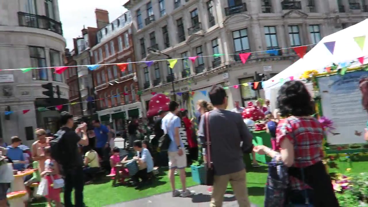 Visitors on a temporary lawn beneath colourful bunting on Regent Street