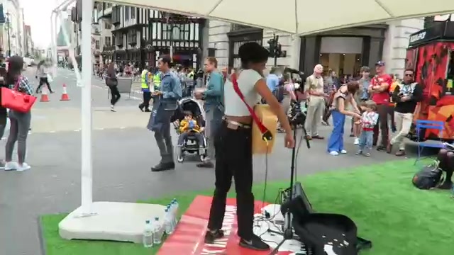 Guitarist performing beside temporary green turf at Summer Streets